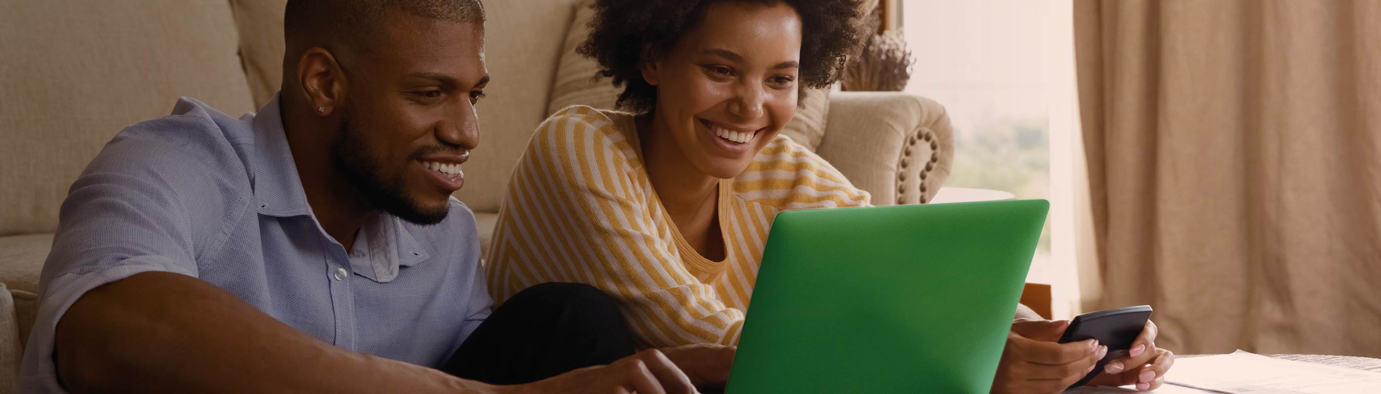 Glimlachend koppel dat aan een salontafel voor een computer zit