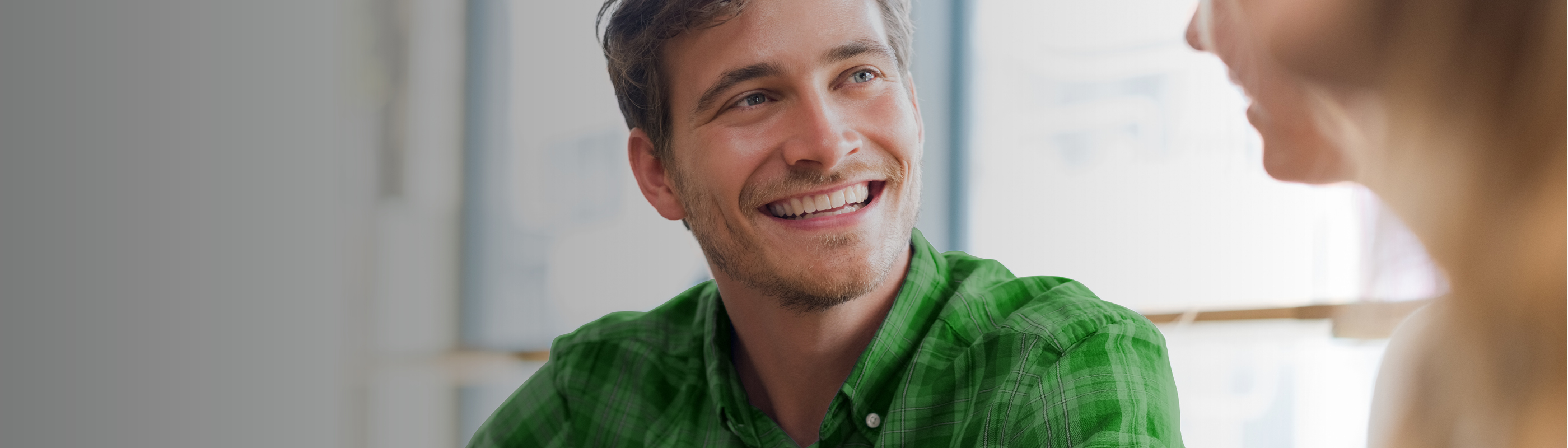 Jonge man in een ruitenhemd die naar een vrouw glimlacht
